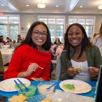 Two teenage girls smile decorating Christmas cookies